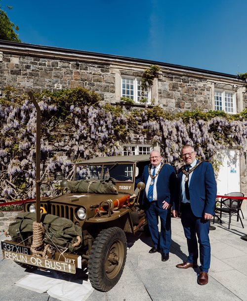 Mayor and Deputy Mayor standing beside a WWII jeep